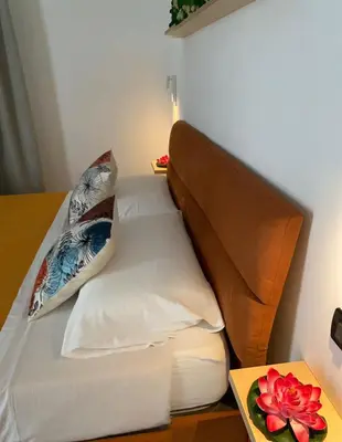 a bed with white sheets and pillows next to a table at Fiori di Quercia in Carini