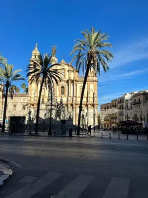a large building with palm trees in front of it at Casa Vacanza Edy in Palermo