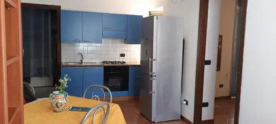 a kitchen with blue cabinets and a table and a refrigerator at Casa Vacanza Edy in Palermo