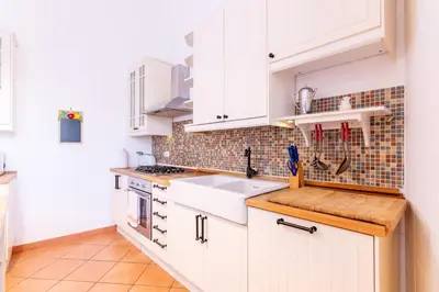 a white kitchen with white cabinets and a sink at Viola's Luxury House in Palermo