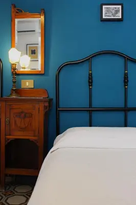 a blue bedroom with a bed and a table with a mirror at La Via delle Biciclette in Palermo