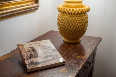 a vase sitting on a table next to a book at A Casa del Gioielliere in Palermo