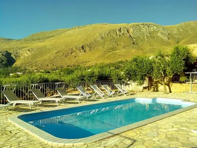 a swimming pool with lounge chairs and a mountain at Baglio Poma in Castelluzzo