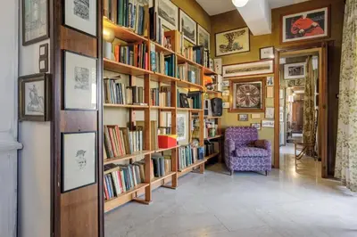 a library with wooden shelves filled with books at Artist penthouse 2 in Palermo