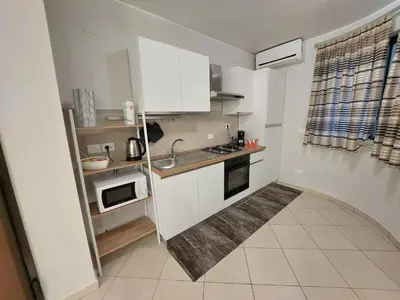 a small kitchen with white cabinets and a sink at Vespucci Holiday in Casteldaccia