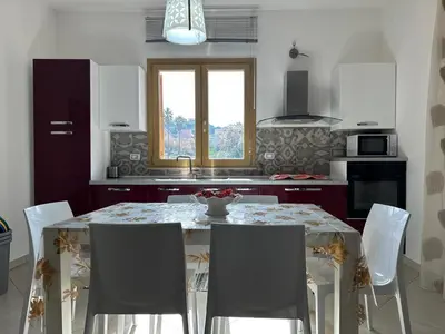 a kitchen with a table with chairs and a window at Mare Blu Apartament in Balestrate