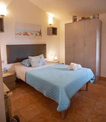 a bedroom with a bed with a blue blanket at Villa Carilù in Altavilla Milicia