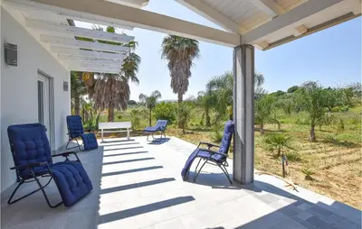 a porch with blue chairs and a table and trees at Awesome Home In Partinico With Wi-Fi in Partinico
