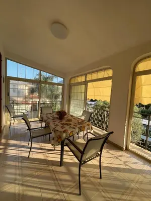 a dining room with a table and chairs and windows at Villa Nasus in Carini