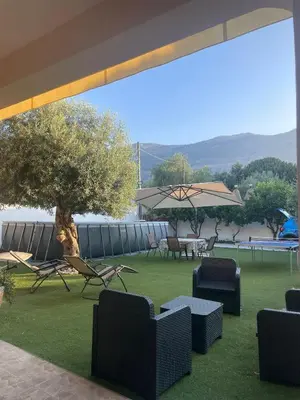 a patio with chairs and tables and an umbrella at Villa Nasus in Carini