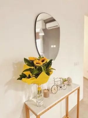 a vase of yellow flowers on a table with a mirror at Serendipity room & relax in Palermo