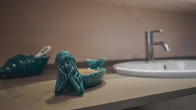 a bathroom counter with a green figurine next to a sink at [jarase] nel centro di Palermo in Palermo