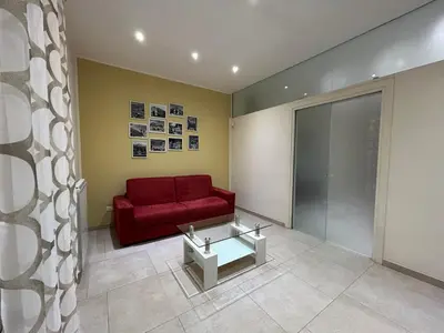 a living room with a red couch and a glass table at A casa di Alli in Palermo