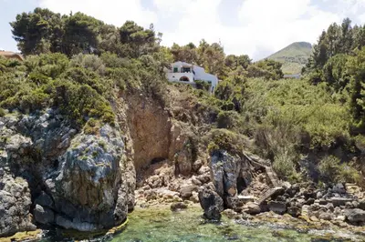 a house on the side of a mountain with water at Villa La Fenice by Wonderful Italy in Castellammare del Golfo