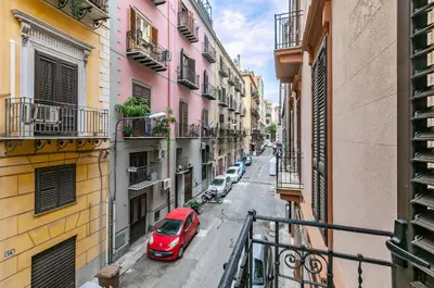 a red car parked on a street between buildings at Teatro Massimo Roomy Flat with Covered Terrace in Palermo