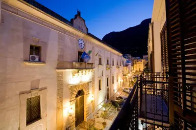 a city street at night with a clock on a building at Sicilia Ovest - Domus Mariae Charming Apartments with Balcony in Castellammare del Golfo