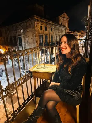 a woman sitting at a table on a balcony at Heritage Collection Palermo B&B in Palermo
