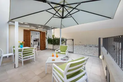 a patio with a table and chairs and a large umbrella at I Tre Golfi - Villetta Ninfea in San Vito lo Capo