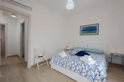 a bedroom with a bed with a blue and white comforter at I Tre Golfi - Villetta Ninfea in San Vito lo Capo