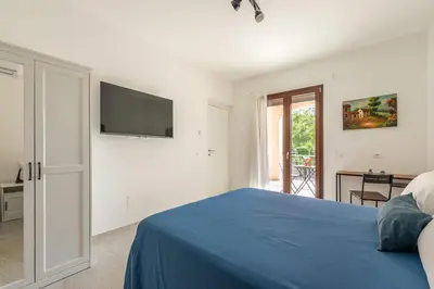 a white bedroom with a blue bed and a tv at Villetta Hilda by Wonderful Italy in Mondello