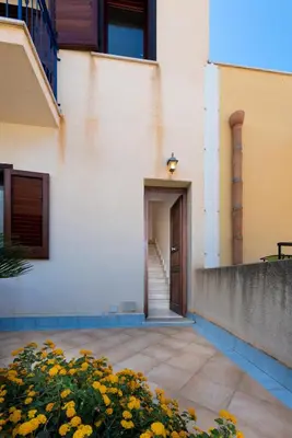 a building with a door and some yellow flowers at Paprica&Zenzero in San Vito lo Capo