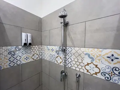 a shower in a bathroom with tiles on the wall at Baron’s Suites in Palermo