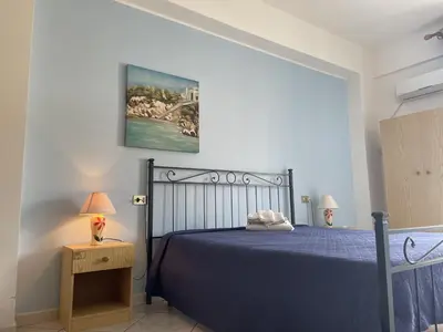 a bedroom with a blue bed and a painting on the wall at Case Vacanza Trappetodavivere in Trappeto