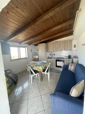 a living room with a blue couch and a kitchen at Case Vacanza Trappetodavivere in Trappeto