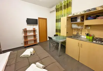 a room with a bed and a kitchen with a table at Monfenera Little Apartments in Palermo