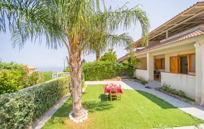a palm tree in the yard of a house with a table and chairs at 2 Bedroom Amazing Home In Trabia in Trabia