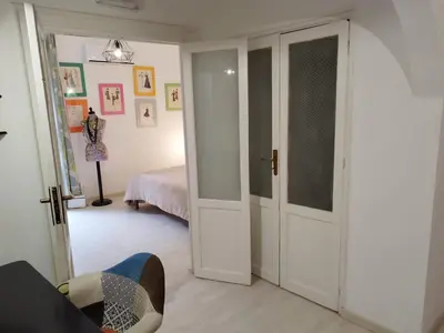 a room with a door and a bedroom with a bed at The tailor's house in Palermo