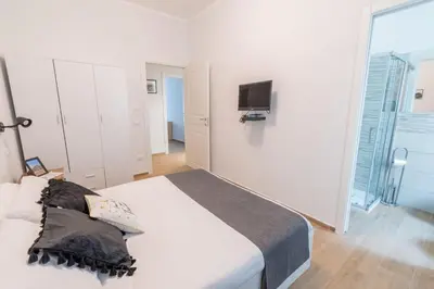 a white bedroom with a bed and a tv at LE TRE CHIAVI Apartment in Palermo