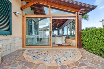 a glass house with a patio and a table at Villa vista mare e piscina privata ad Alcamo in Alcamo