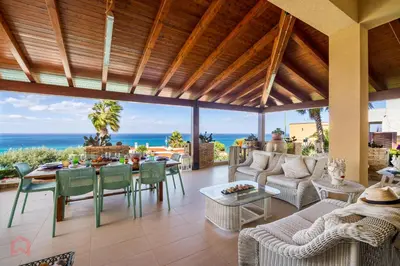 a living room with a table and chairs and the ocean at Villa vista mare e piscina privata ad Alcamo in Alcamo