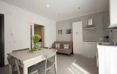 a kitchen and living room with a white table and chairs at Holiday House Vitruvian in Terrasini