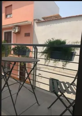 a table and chair on a balcony with a building at Holiday House Vitruvian in Terrasini
