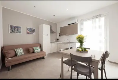 a kitchen and living room with a table and a couch at Holiday House Vitruvian in Terrasini