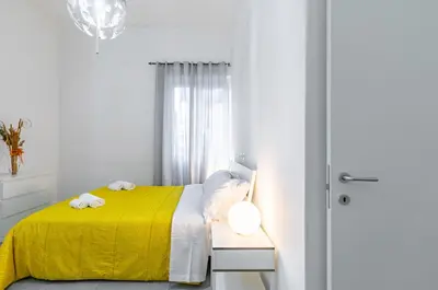 a white bedroom with a yellow bed and a window at GuestHost - Ballarò Market Cozy Apartments in Palermo