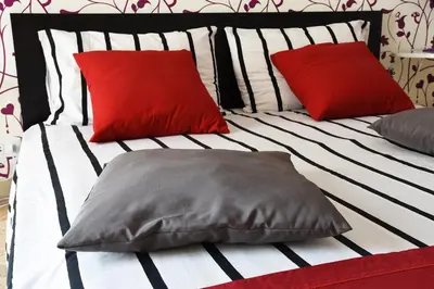 a bed with red and white pillows on it at Papillon BnB in Palermo