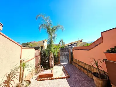 a courtyard with a fence and a palm tree at Costa Mediterranea Holiday Homes in Campofelice di Roccella