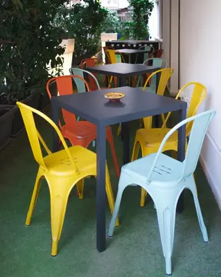 a group of tables and chairs with colorful chairs at Hostelò - Luxury Hostel in Palermo