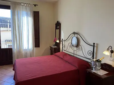 a bedroom with a red bed with a mirror and a window at Kalura B&B in Macari