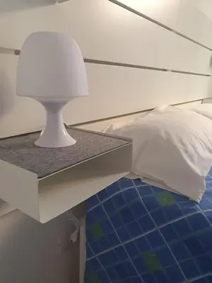 a bed with a table with a lamp on it at La Casetta del piano di sopra in Palermo