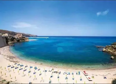 a beach with chairs and umbrellas in the water at Casa gli Oleandri in Castellammare del Golfo