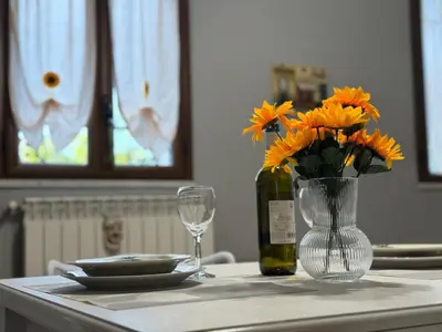 a table with a vase of orange flowers and a wine bottle at Casa del mare Mely in Ficarazzi