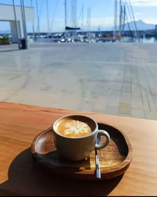 a cup of coffee on a wooden plate with a spoon at Appartamento Vista Stazione in Palermo