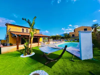 a hammock in a yard next to a swimming pool at Villa CLARA in Altavilla Milicia