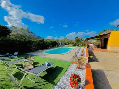 a backyard with a swimming pool and two chairs at Villa CLARA in Altavilla Milicia