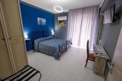a bedroom with blue walls and a bed and a table at Room 112 Oltremare in Bagheria