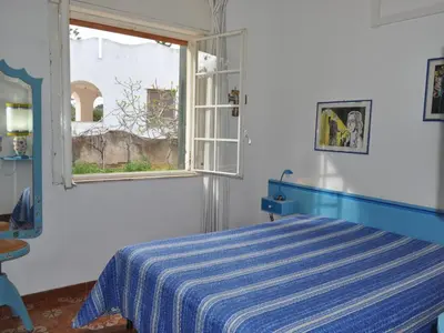 a bedroom with a blue and white bed and a window at CASE VACANZA PERLA DEL SUD in San Vito lo Capo